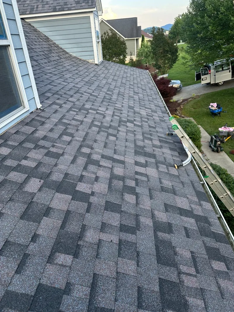 Looking down the slope of a new gray architectural shingle roof over a neighborhood
