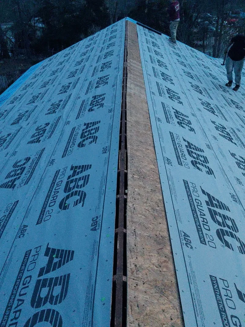 Blue synthetic underlayment at the ridge of a roof being prepared for metal panels