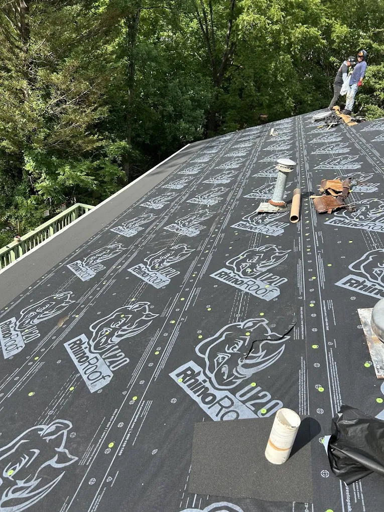 A crew member on a steep roof slope laying synthetic underlayment
